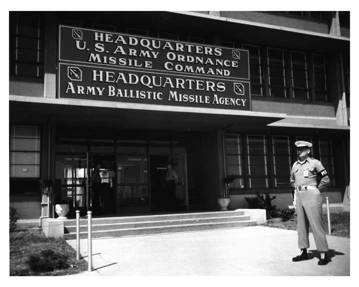Photo of U.S. Army Ordnance Missile Command and Army Ballistic Missile Agency headquarters building entrance, with an Army military policeman in foreground.