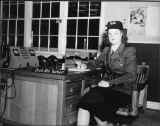 Black and white photo of uniformed woman sitting at desk