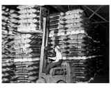 Black and white image of man loading weapons on forklift
