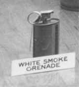 Black and white photo of a canister with a label in front of it "White smoke grenade"