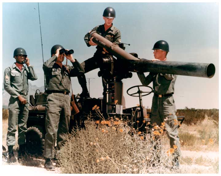 Photo of an Army staff sergeant and 3 troops employing a TOW missile system mounted on a M274 Mechanical Mule.  The staff sergeant is on the radio, one soldier is looking through binoculars, while two soldiers are loading a missile in to the launch tube.