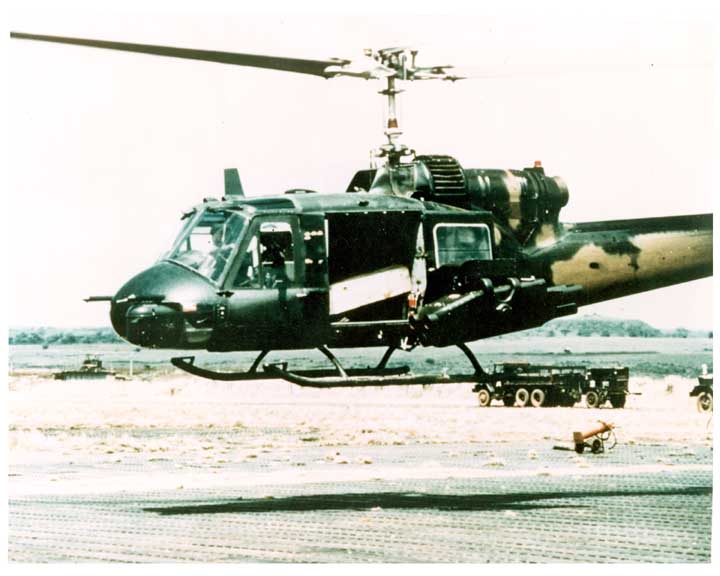 Photo of a TOW missile mounted on a UH-1 Huey Utility Helicopter, helicopter in hover.